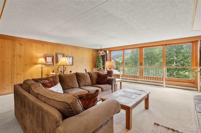 carpeted living room with a wealth of natural light, wooden walls, and a textured ceiling