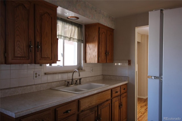 kitchen with white fridge, sink, backsplash, and light hardwood / wood-style floors