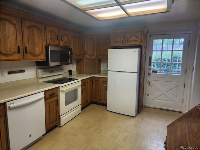 6961 E Arkansas Ave, Denver, CO 80224 - kitchen with white appliances, brick patterned floors, light countertops, and brown cabinetry