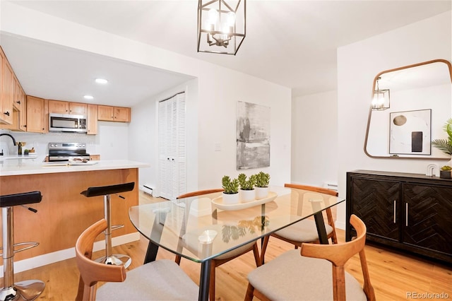 dining area with sink, light hardwood / wood-style flooring, and a chandelier