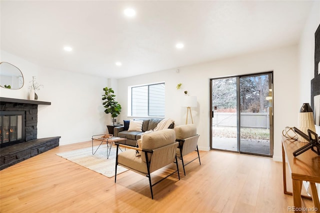 living room featuring light hardwood / wood-style flooring and a stone fireplace