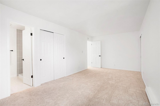 unfurnished bedroom featuring connected bathroom, a closet, and light carpet