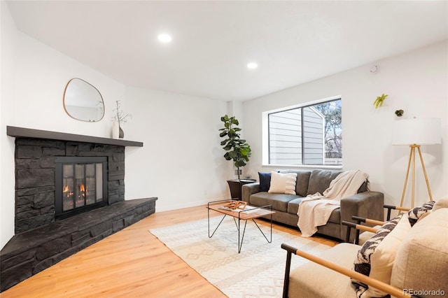 living room featuring wood-type flooring and a stone fireplace