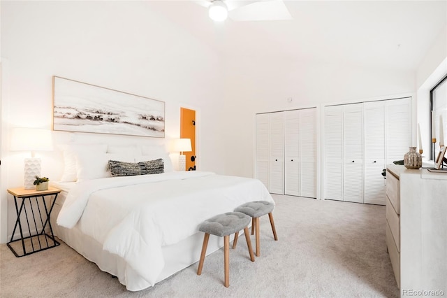 bedroom featuring a towering ceiling, two closets, ceiling fan, and light carpet