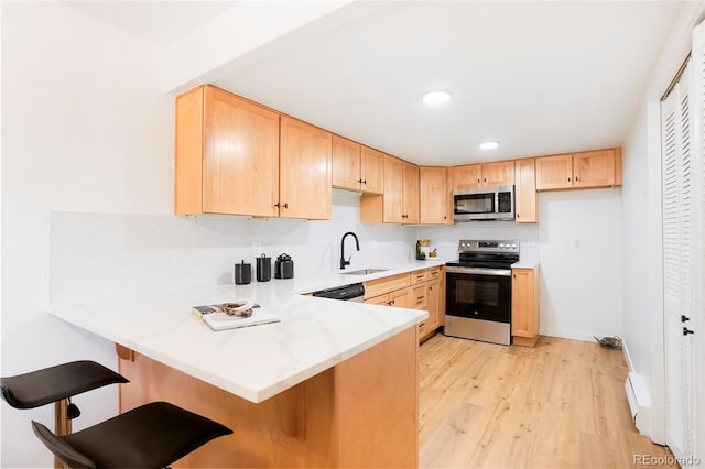 kitchen featuring sink, a kitchen breakfast bar, light brown cabinetry, and appliances with stainless steel finishes