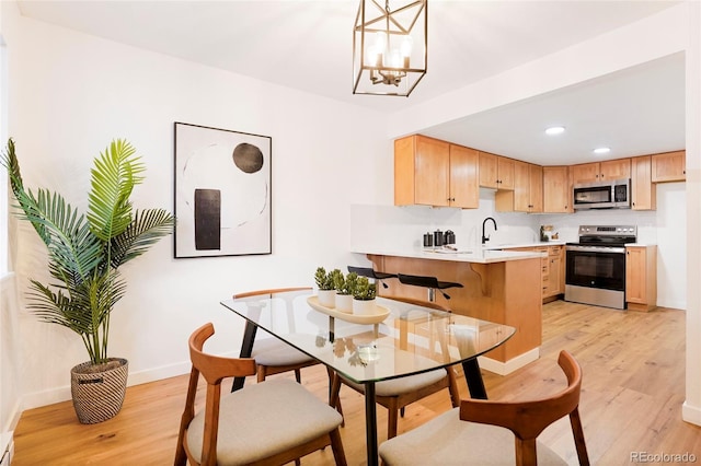 dining space with sink, a chandelier, and light hardwood / wood-style floors