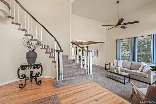 interior space featuring ceiling fan, baseboards, a high ceiling, and wood finished floors