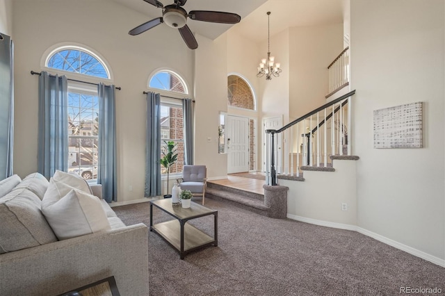 living room with stairway, baseboards, a high ceiling, carpet flooring, and ceiling fan with notable chandelier