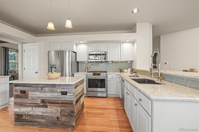 kitchen featuring tasteful backsplash, light wood-style flooring, appliances with stainless steel finishes, white cabinets, and a sink