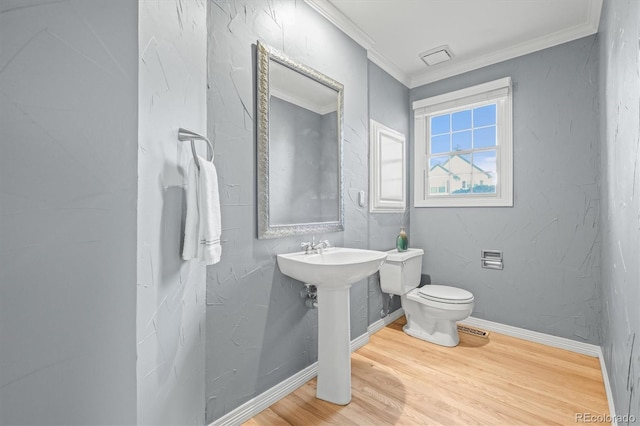 half bathroom with baseboards, toilet, wood finished floors, and crown molding