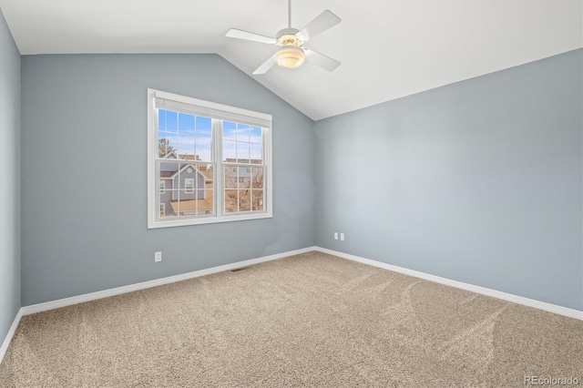 empty room with visible vents, lofted ceiling, a ceiling fan, carpet floors, and baseboards