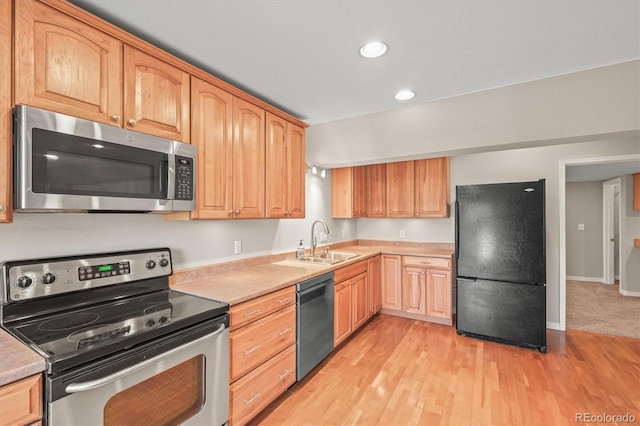 kitchen featuring light wood-style flooring, appliances with stainless steel finishes, light countertops, and a sink