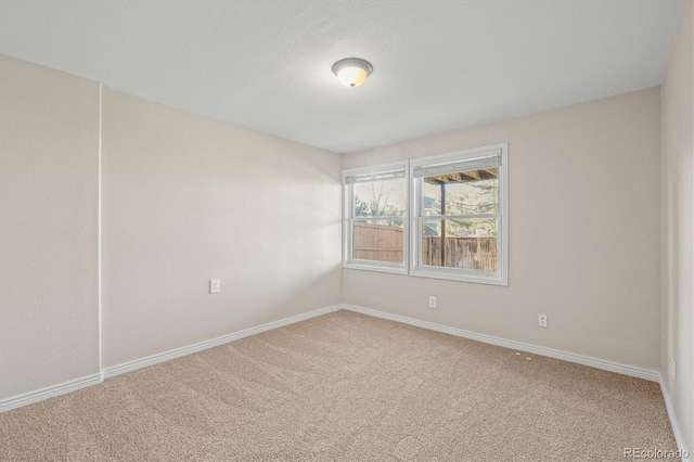 carpeted empty room featuring baseboards