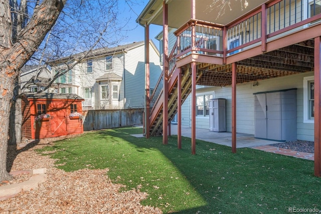 view of yard featuring stairway, a storage shed, an outdoor structure, a wooden deck, and a patio area