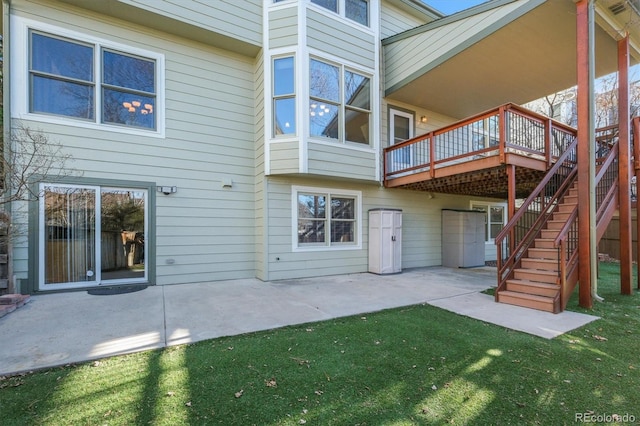 rear view of property with a lawn, a deck, stairs, and a patio area