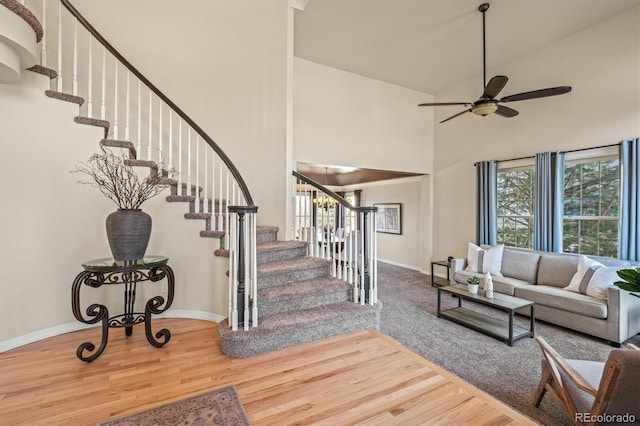 interior space featuring wood finished floors, a towering ceiling, a ceiling fan, and baseboards