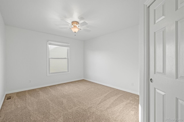 empty room with baseboards, a ceiling fan, visible vents, and carpet floors