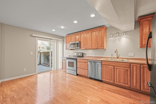 kitchen with light wood-style flooring, recessed lighting, a sink, light countertops, and stainless steel appliances