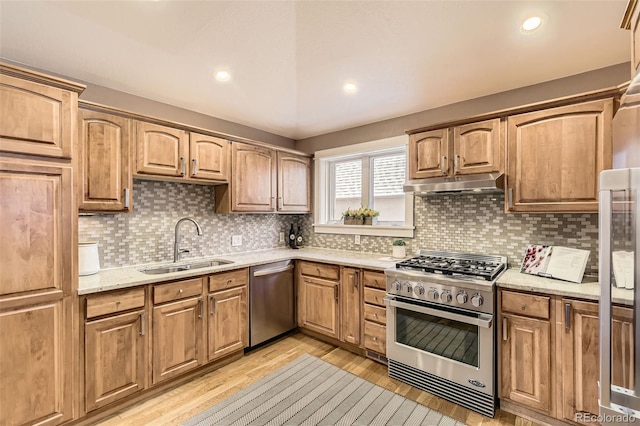 2692 N Raleigh St, Denver, CO 80212 - kitchen with appliances with stainless steel finishes, under cabinet range hood, light wood finished floors, light stone counters, and tasteful backsplash