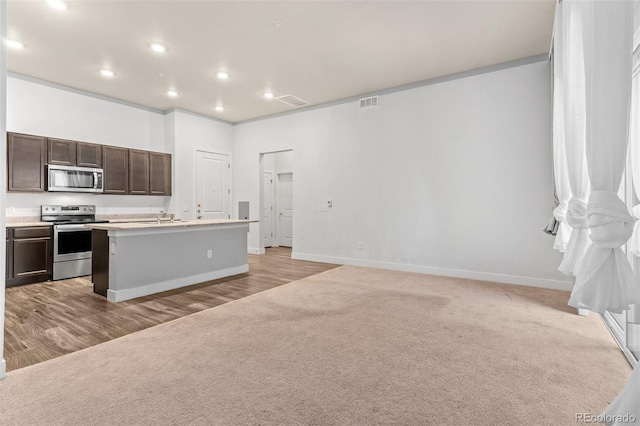 14301 E Tennessee Ave Unit 109, Aurora, CO 80012 - kitchen with stainless steel appliances, dark brown cabinetry, an island with sink, recessed lighting, and baseboards