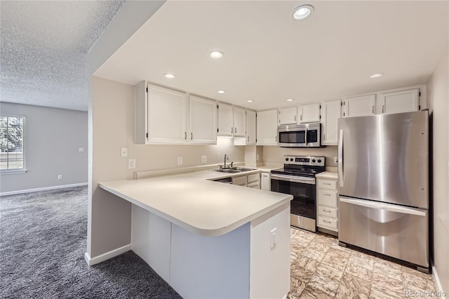 kitchen featuring kitchen peninsula, appliances with stainless steel finishes, light carpet, sink, and white cabinetry