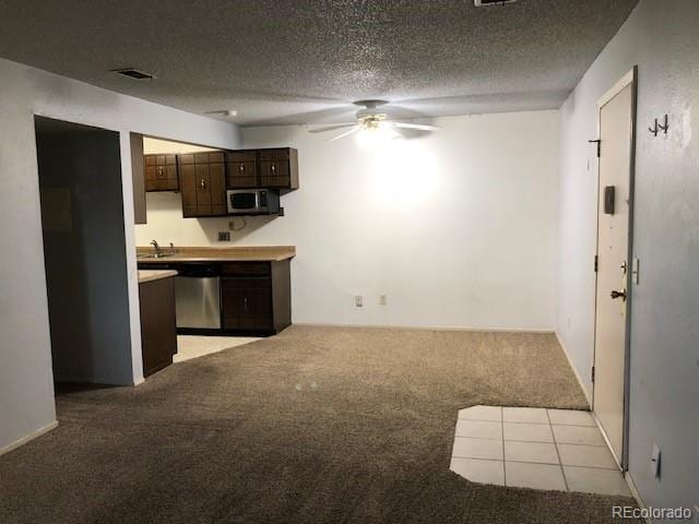 kitchen featuring a textured ceiling, dark brown cabinets, light carpet, and appliances with stainless steel finishes