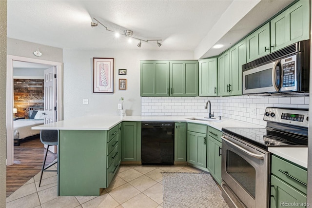 kitchen with green cabinetry, stainless steel appliances, kitchen peninsula, and sink