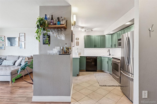 kitchen featuring light tile patterned flooring, appliances with stainless steel finishes, tasteful backsplash, sink, and green cabinets