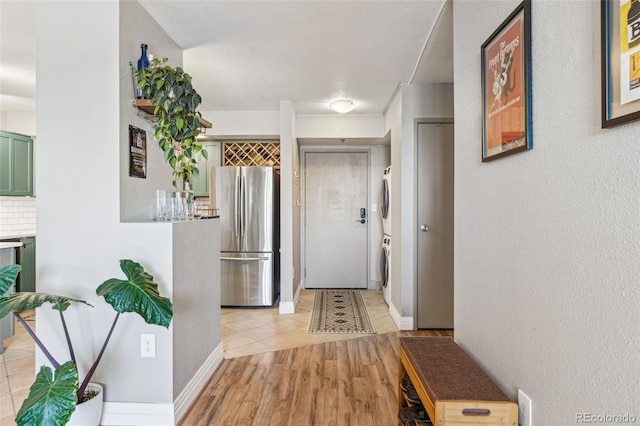 hall with stacked washer and clothes dryer and light hardwood / wood-style flooring