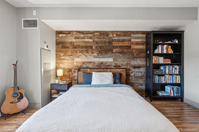 bedroom with wooden walls and dark hardwood / wood-style flooring