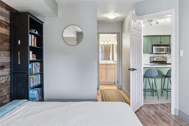 bedroom featuring connected bathroom and light hardwood / wood-style floors