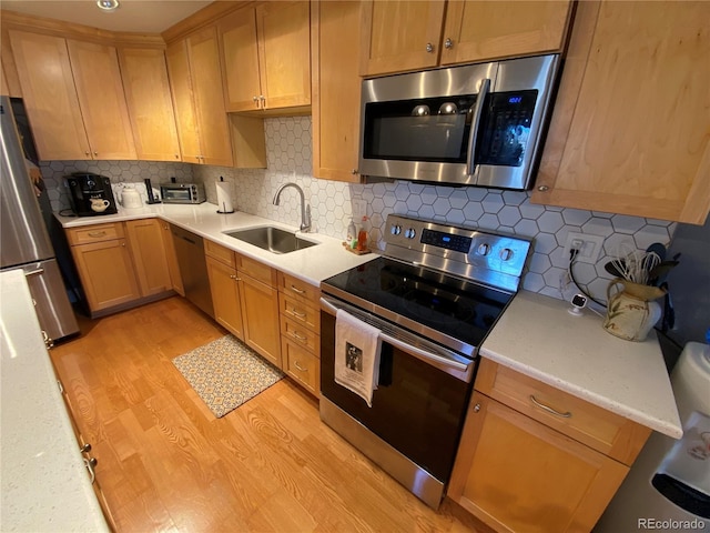 kitchen with decorative backsplash, sink, light wood-type flooring, and stainless steel appliances