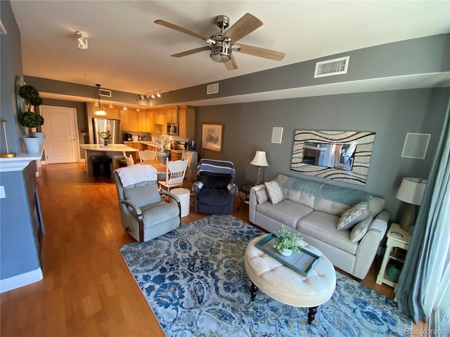 living room with ceiling fan and dark hardwood / wood-style flooring