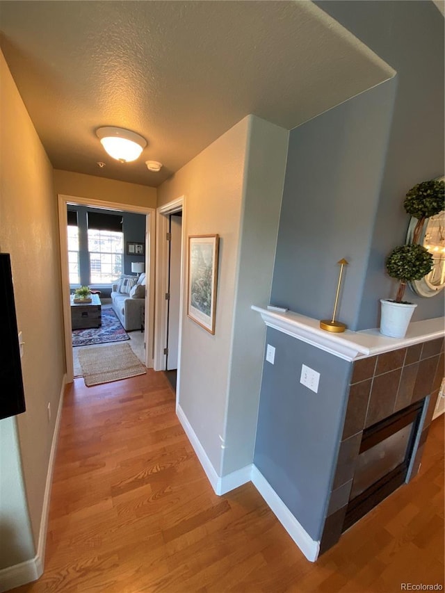 corridor with a textured ceiling and light hardwood / wood-style floors