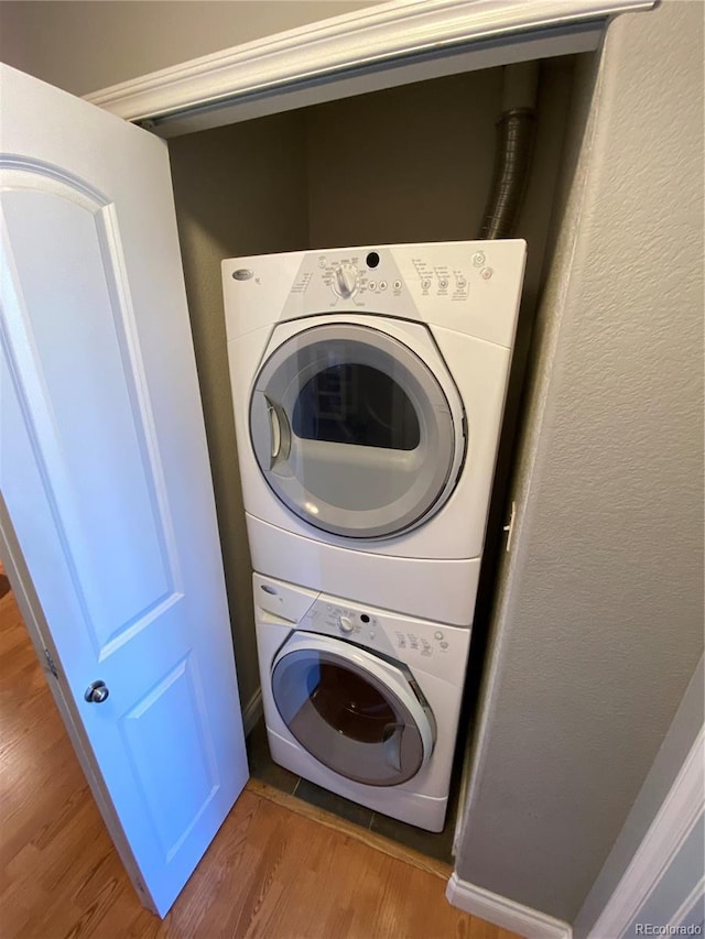 clothes washing area with wood-type flooring and stacked washing maching and dryer