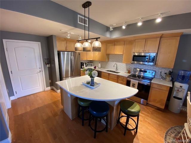 kitchen with sink, tasteful backsplash, decorative light fixtures, light hardwood / wood-style floors, and stainless steel appliances