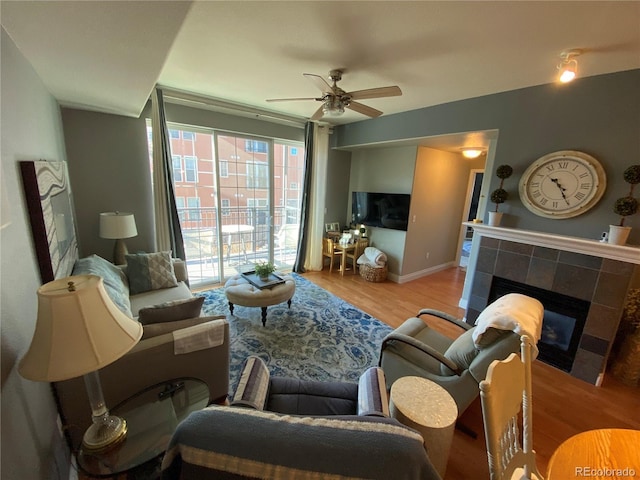 living room featuring ceiling fan, a fireplace, and light hardwood / wood-style flooring