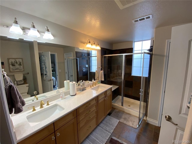 bathroom with vanity, toilet, a shower with shower door, and a textured ceiling