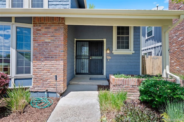 property entrance with fence and brick siding
