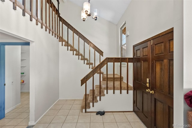 entryway with a high ceiling, light tile patterned floors, a chandelier, and stairway