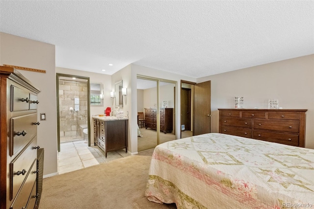 bedroom with light carpet, connected bathroom, a textured ceiling, light tile patterned floors, and baseboards