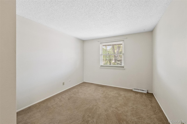carpeted empty room with a textured ceiling and baseboards
