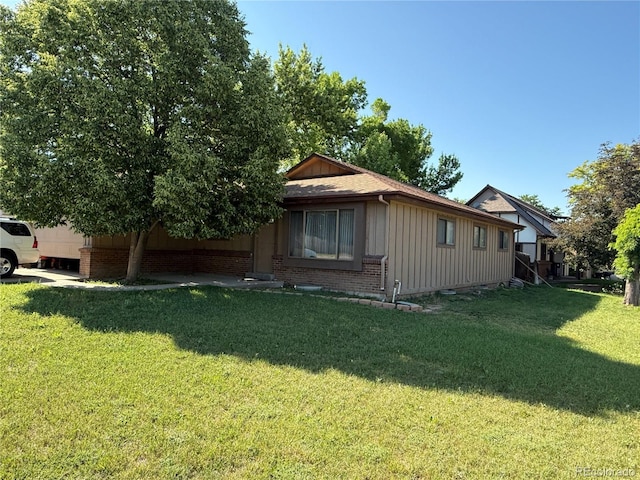 8995 E Cornell Ave, Denver, CO 80231 - view of side of home with board and batten siding, a yard, and brick siding