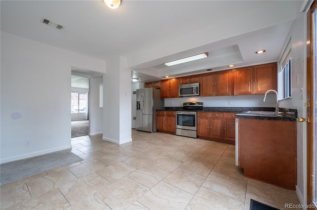 kitchen with sink, light colored carpet, appliances with stainless steel finishes, and a tray ceiling