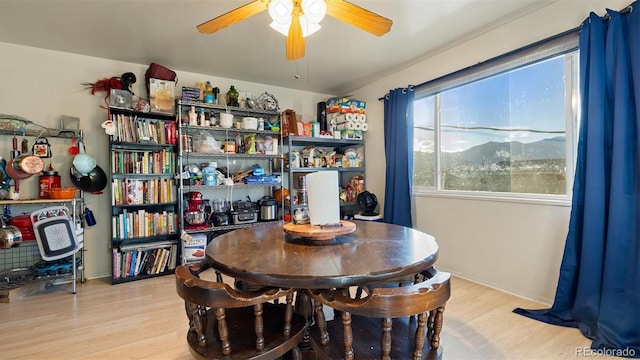 dining area with a mountain view, ceiling fan, and light wood-type flooring