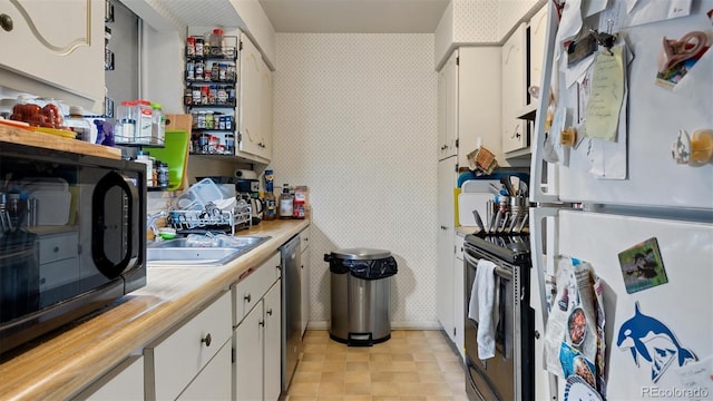 kitchen with stainless steel appliances, white cabinetry, and sink