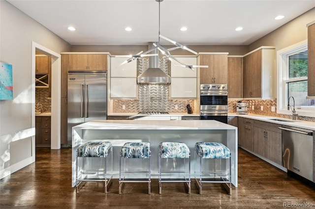 445 Forest St, Denver, CO 80220 - kitchen with stainless steel appliances, wall chimney exhaust hood, light countertops, a breakfast bar area, and decorative backsplash