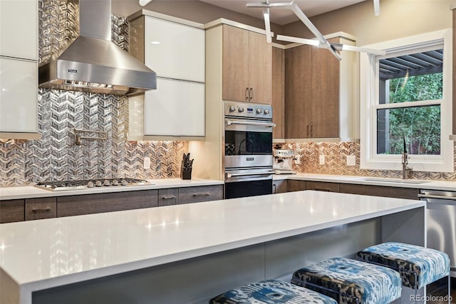 445 Forest St, Denver, CO 80220 - kitchen with wall chimney range hood, stainless steel appliances, light countertops, tasteful backsplash, and modern cabinets