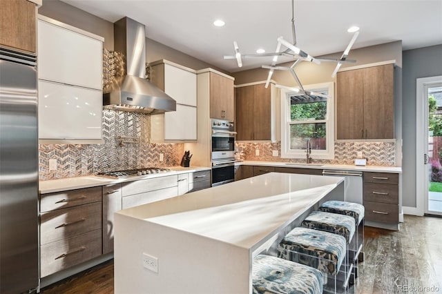 445 Forest St, Denver, CO 80220 - kitchen with wall chimney exhaust hood, appliances with stainless steel finishes, light countertops, dark wood-type flooring, and recessed lighting