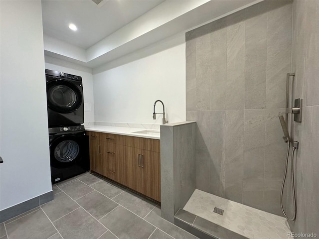 laundry area with a sink, light tile patterned floors, and stacked washer / dryer